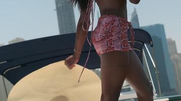 Young swarthy woman in a white bikini and a light dress on board a private boat against the backdrop of the city video