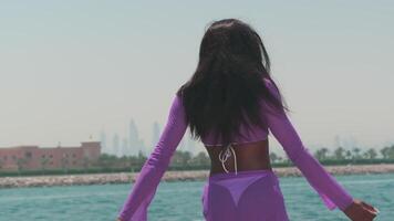 Dubai, UAE - 5 22 2021. Young swarthy woman in a white bikini and a light dress on board a private boat against the backdrop of the city video