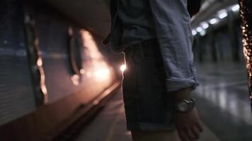 un joven mujer con largo negro pelo en ropa de deporte es esperando para el llegada de el tren a el subterráneo metro estación video