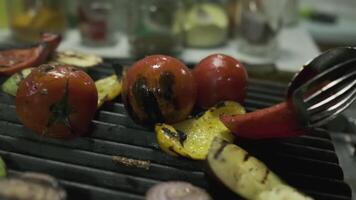 The chef transfers the roasted vegetables from the grill to a large container with metal tongs video