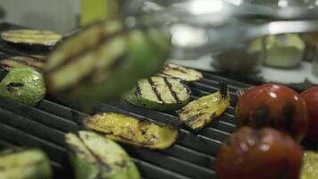 The chef transfers the roasted vegetables from the grill to a large container with metal tongs video