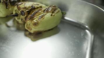 The chef with white-gloved hands shifts fried vegetables from the grill into a large container video