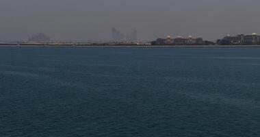 a zangão moscas sobre a ondas do a mar para a cidade em a costa. dubai, Unidos árabe Emirados video