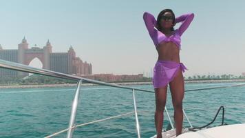 Young swarthy woman in a white bikini and a light dress on board a private boat against the backdrop of the city video