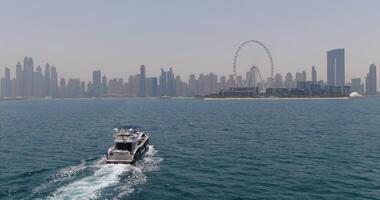 Dubai, UAE - 5 22 2021. A drone flies by a private boat sailing on a calm sea towards the city video