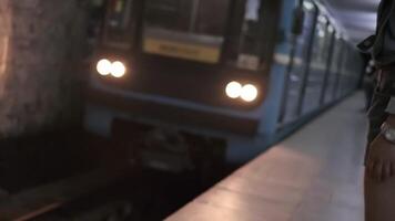 une Jeune femme avec longue noir cheveux dans tenue de sport est attendre pour le arrivée de le train à le souterrain métro station video