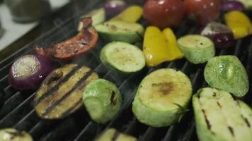 The chef turns over the vegetables that are fried on the grill with metal tongs video