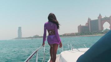 Young swarthy woman in a white bikini and a light dress on board a private boat against the backdrop of the city video