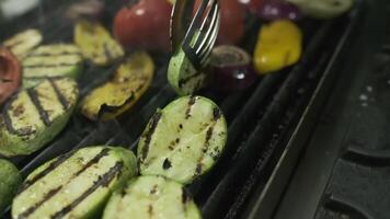 The chef turns over the vegetables that are fried on the grill with metal tongs video