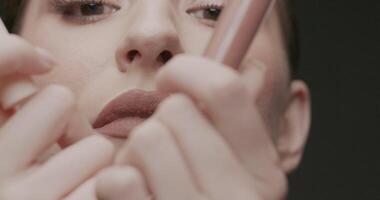 Close-up of young elegant woman with a tube of lipstick in her hands video