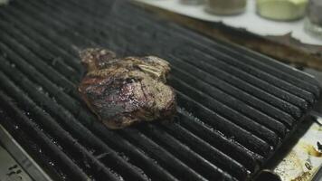 The chef uses metal tongs to transfer the grilled meat steak and grill to a cutting board video