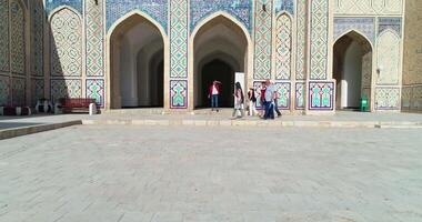 bukhara, Oezbekistan - 4 11 2022. de dar vliegt in de omgeving van de binnenplaats van de oude complex ulugbek madrasah met een groep van toeristen. oud bukhara, Oezbekistan. video