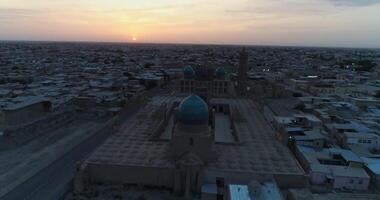 A drone flies over the architectural complex Poi-Kalon among old houses in Bukhara, Uzbekistan. Early cloudy morning video