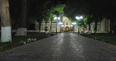 drone plus de nuit ruelle illuminé par lanternes dans de face de le complexe nadir divan-begi madrasa, Boukhara. video