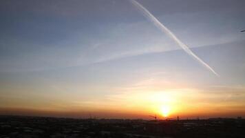 zonsondergang in de stad Aan een bewolkt avond. in de lucht, de spoor van een vliegend vlak. video