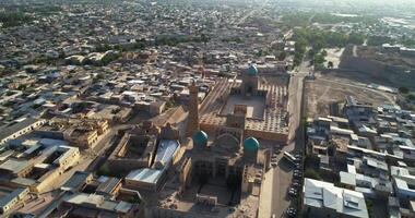 The drone flies over the ancient tower of the complex Lyab-i Hauz with groups of tourists. Around old Bukhara, Uzbekistan. video