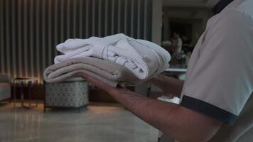 A staff in an expensive luxury hotel hands over a rolled-up towel to a guest video