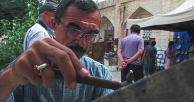 bukhara, Oezbekistan - 4 14 2023. een meester reliëfdrukker creëert een patroon Aan een koper bord gebruik makend van oude technologieën. video