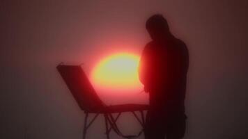 silhouette de un artiste avec un chevalet à le coucher du soleil contre le Contexte de le Soleil. video
