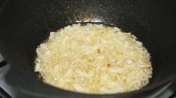 An elderly woman puts pieces of meat in oil boiling in a cauldron. Stir with a wooden spoon. video