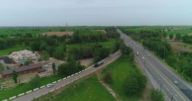 A drone flies over a truck driving on a country road. There are trees and fields around. video