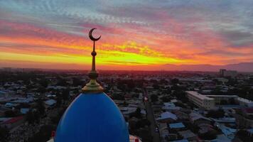een dar vliegt in de omgeving van een moskee in de stad tegen de achtergrond van zonsopkomst. video