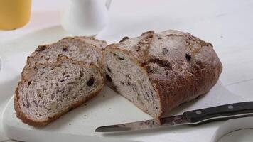 detailopname van gesneden stukken en voor de helft van rogge rozijn brood Aan de wit tafel video