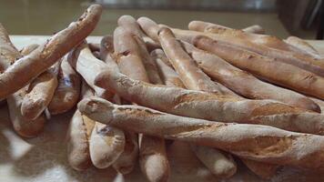 vers gebakken lang baguette brood liggen Aan de houten tafel besprenkeld met meel in een stapel video