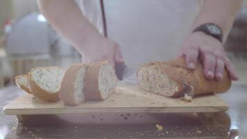 Baker is cutting baked Dutch bread with raisins and dried apricots with knife video