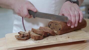 Baker is cutting baked Dutch bread with raisins and dried apricots with knife video