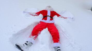 de kerstman claus maakt sneeuw engelen in de sneeuw. humor, winter plezier, de kerstman is moe en dronken video