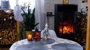 metall noir poêle, brûlant foyer cheminée dans blanc de fête intérieur de maison est décoré pour Noël et Nouveau année, Noël arbre. bois de chauffage dans le tas de bois, confortable et chauffage de Accueil video