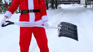 Santa claus Tanzen komisch mit ein Schaufel und Theaterstücke mögen ein Gitarre und reinigt Schnee mit Schaufel im Winter draußen nach ein Schneefall. Humor zum Weihnachten und Neu Jahr video