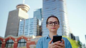 Caucasian woman in glasses walking around the city and using smartphone video