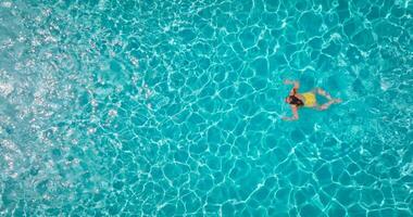 topo baixa Visão do uma mulher dentro amarelo roupa de banho natação dentro a piscina. video