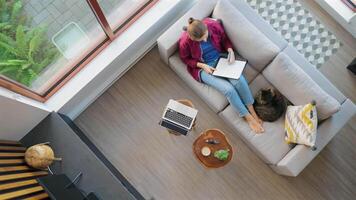 Overhead view of woman writing notes, lying on couch at home video