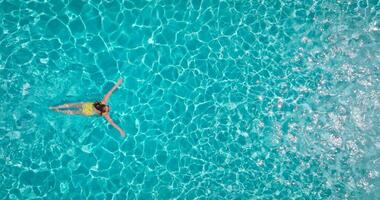 Top down view of a woman in yellow swimsuit swimming in the pool. video