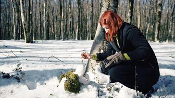 mujer creando y decorando un monigote de nieve en el montaña video