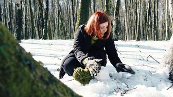 Happy woman creating a snowman near a tree video