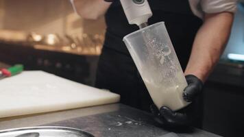 Cook uses immersion mixer blender to prepare a sauce video