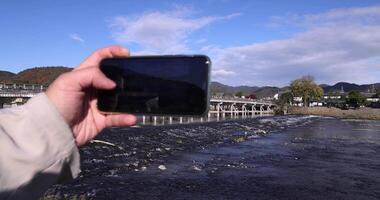 un teléfono inteligente disparo togetsukyo puente cerca katsuragawa río en Kioto en otoño video