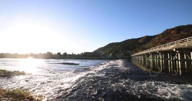 A dawn of Togetsukyo bridge near Katsuragawa river in Kyoto in autumn wide shot video