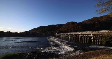 A dawn of Togetsukyo bridge near Katsuragawa river in Kyoto in autumn wide shot video