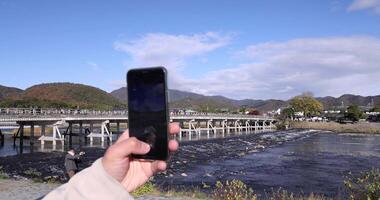 un' smartphone tiro togetsukyo ponte vicino katsuragawa fiume nel kyoto nel autunno video