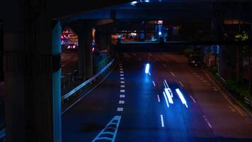 A night timelapse of the traffic jam at the city street under the highway in Tokyo tilt video
