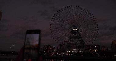 un oscuridad de giratorio ferris rueda disparo por teléfono inteligente en Yokohama video