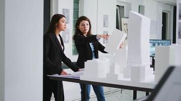 Manufacturing engineers looking at building model shape to create the perfect measurements for property remodeling. Architectural experts team working with industrial tools at creative agency. video