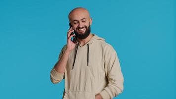 Arab person answering phone call in front of camera, talking to his friends on remote chat with smartphone. Young adult using mobile phone communication to discuss with people. Camera 1. video