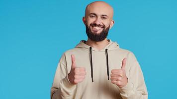 Middle eastern person giving thumbs up on camera, feeling cheerful and showing his approval. Arab adult doing okay or like symbol in studio, expressing positivity and agreement. Camera 2. video