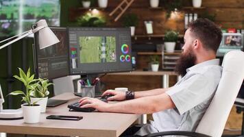 Video editor working in professional software. He uses a dual screen setup and works in modern designed studio office